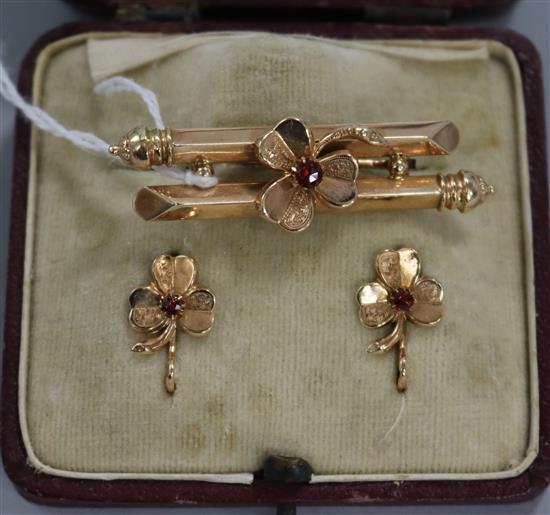 A cased three piece suite of yellow metal and gem set jewellery, comprising a shamrock bar brooch and pair of matching earrings.